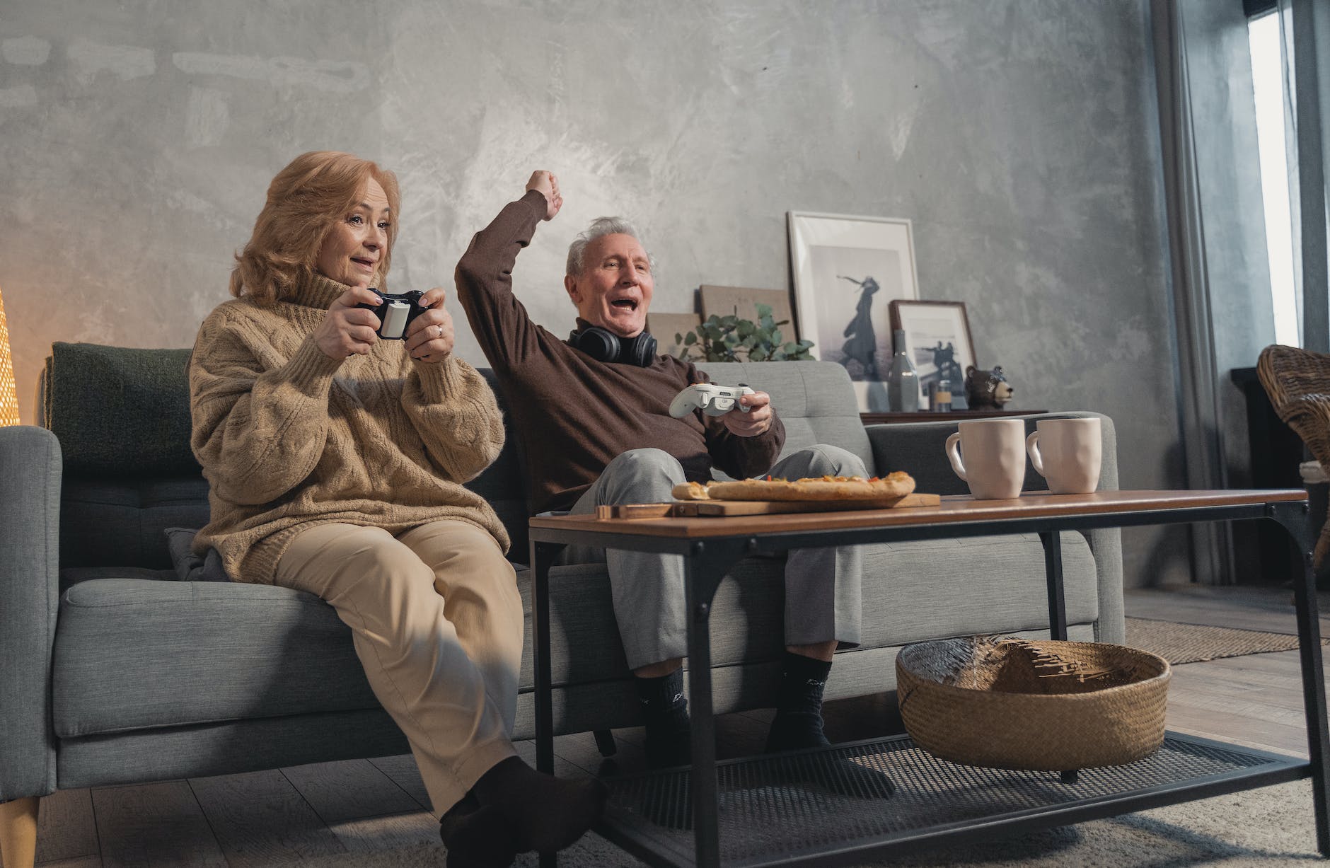 elderly couple sitting on couch playing video games